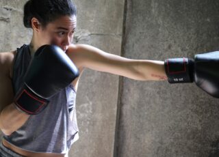 A imagem de uma mulher jovem com luvas de boxe, dando um soco, ilustra a luta quando se tem O “não” na maternidade atípica