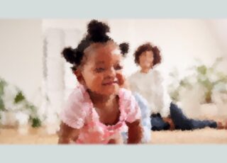 Foto de uma criança preta, 1 ano, desfocada, engatinhando. Ao fundo, sentada no tapete a mãe, também desfocada, observa. Acabei de receber o diagnóstico: meu filho é autista!