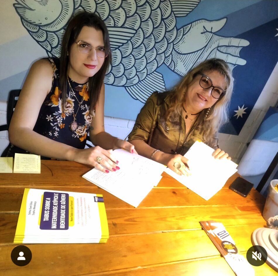 Selma e Sophia em uma mesa, dando autógrafos no livro Nem tudo é o que parece